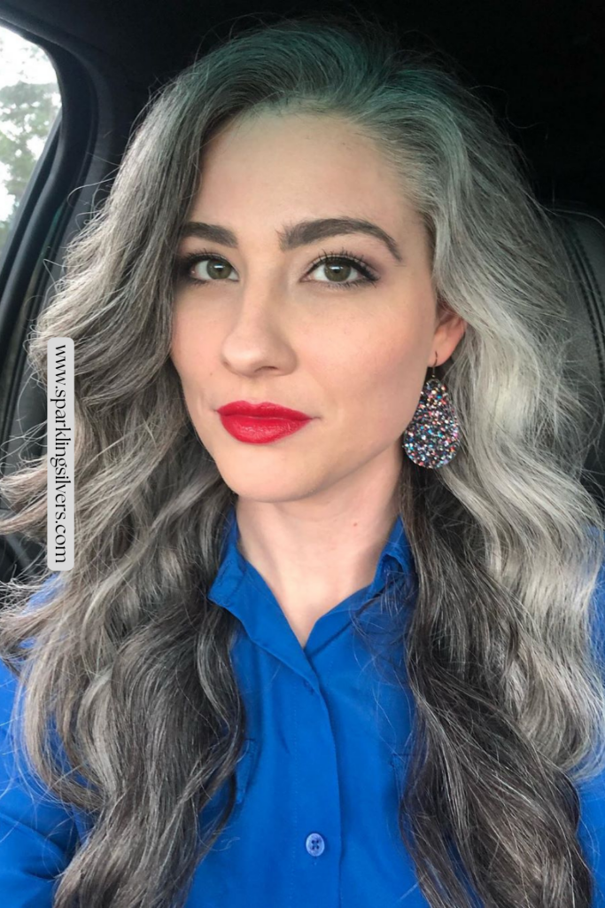Image of a beautiful young woman wearing a blue top and gray hair confidently