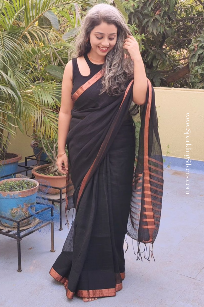 Picture of a young woman with salt and pepper long hair wearing a black saree