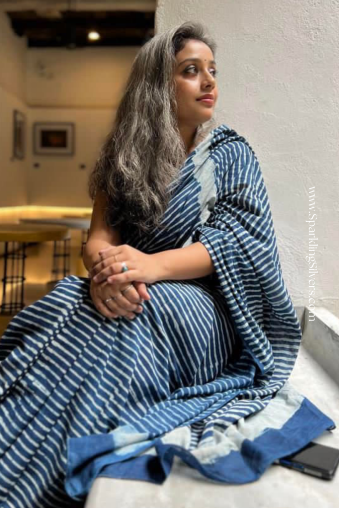 A beautiful young woman with long grey hair wearing a blue saree