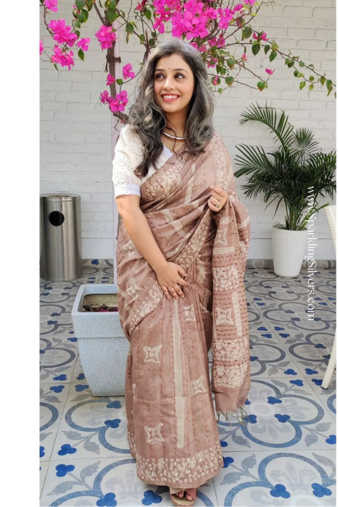 Picture of a woman with long gray hair and a brown saree