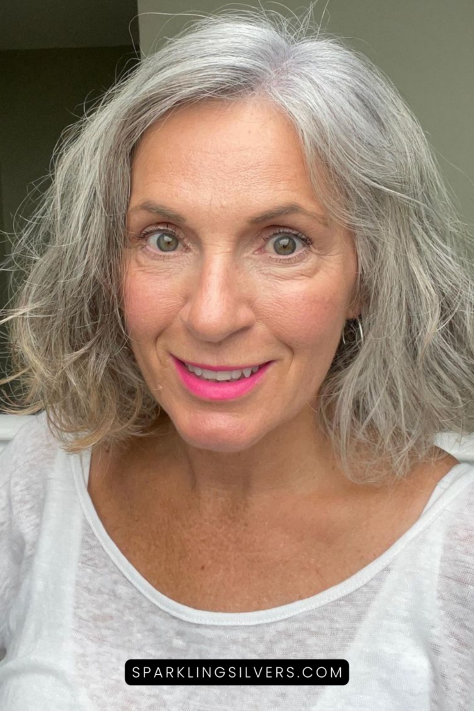 A gray haired woman in white t-shirt and pink lipstick