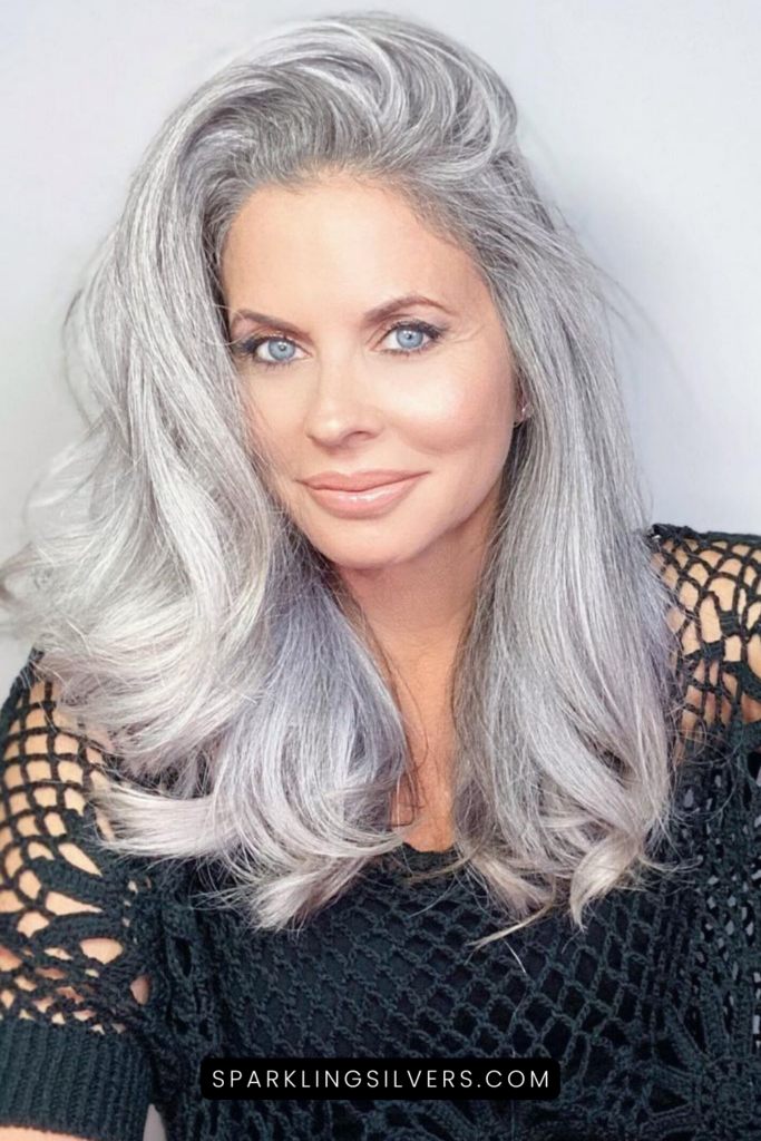 A silver haired woman with blue eyes wearing a black crochet top