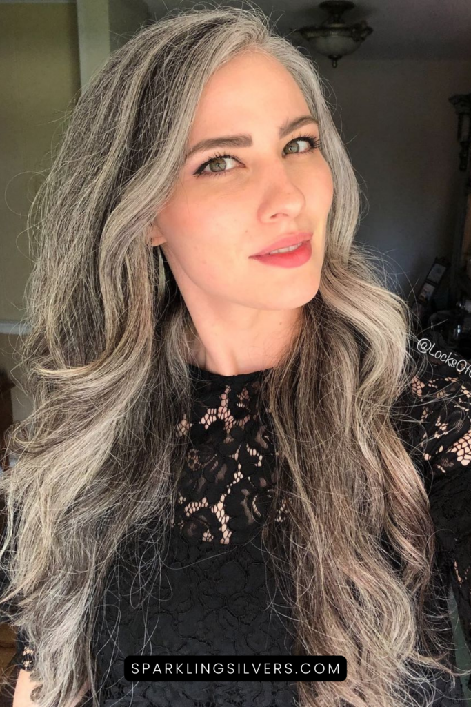 A warm toned grey haired woman wearing a black lace dress