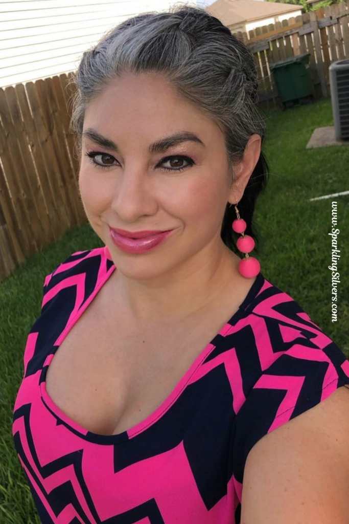 A woman with salt and pepper hair wearing bright colored dress
