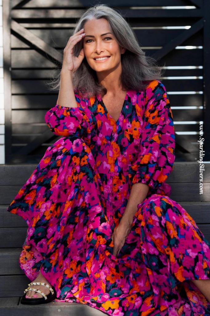 A woman with grey hair and a tonal print dress.