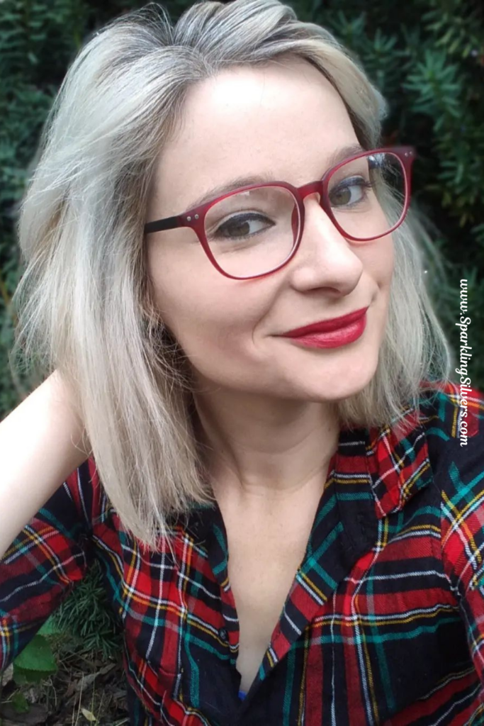 A woman with silver hair wearing specs and a plaid shirt