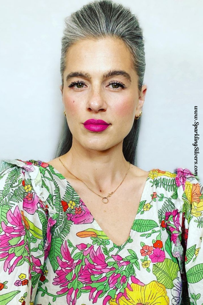 A woman with natural gray hair wearing a floral dress